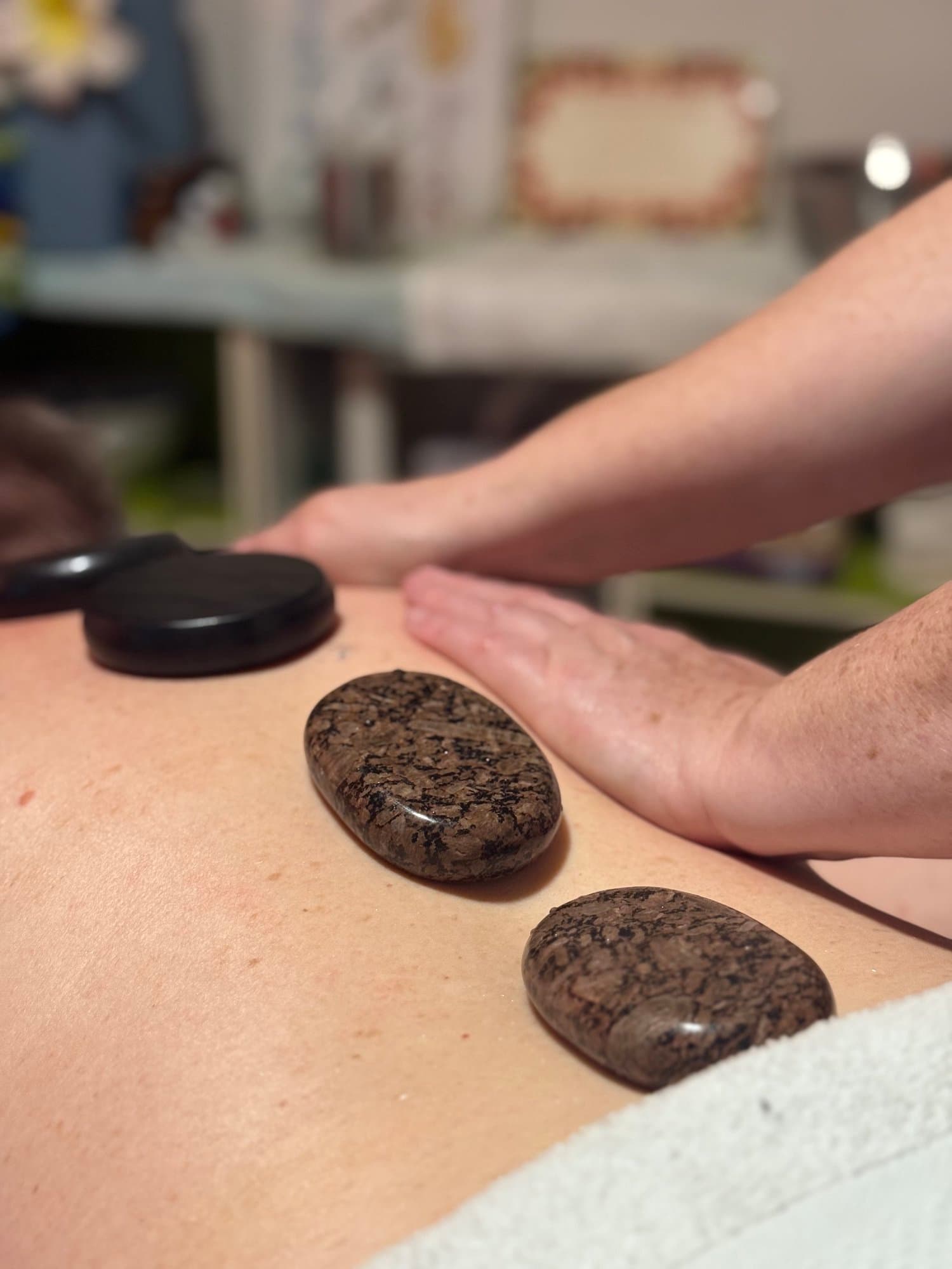 Nic combining hot stones and hands-on massage during a Body and Soul session